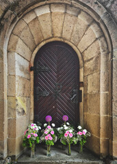 Wall Mural - Vertical shot of a wooden door of a church with flowers