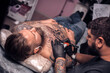 © Mr. Prof - Professional tattooist does tattoo on the skin of his client in tattoo studio