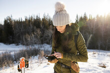 Woman Looking At Phone On Winter Hike