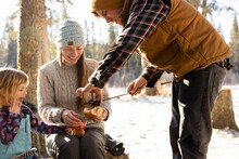 Family Having Winter Barbecue In Snowy Forest