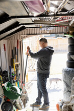 Man Selecting Gardening Tools In Shed