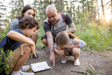 Family Looking At Footprints On Forest Path