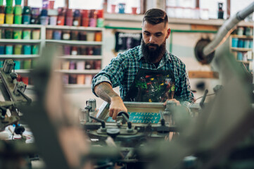 Wall Mural - Male worker using printing machine in a workshop