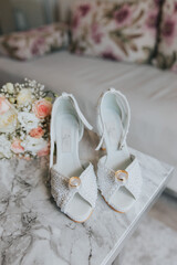 Canvas Print - Bridal bouquet and white heels of the bride on the marble table - wedding preparation