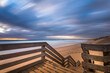 Wooden viewpoint at a beach surrounded by the sea under a cloudy sky with long exposure