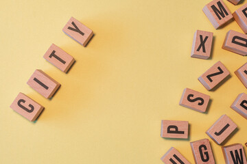 Poster - Word CITY, taken from a pile of wooden letter blocks with yellow background and copy space