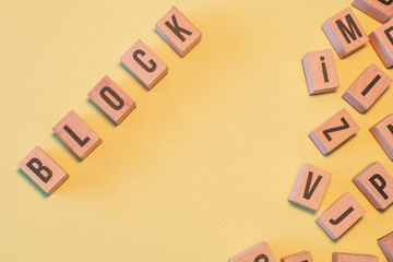 Poster - Word BLOCK, taken from a pile of wooden letter blocks with yellow background and copy space