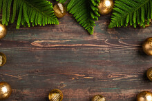 Christmas Pine Leaf With Golden Bauble Decoration On Wooden Table