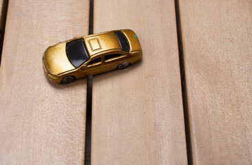 Wall Mural - Close-up shot of a small golden toy car on a wooden surface