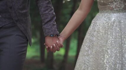 Poster - A wedding couple walking hand in hand in a park