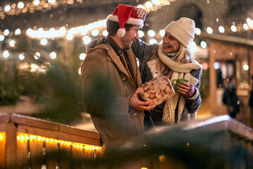 Wall Mural - A young couple in love is enjoying romantic moments under christmas lights in the city. Christmas, New Year, holiday, love