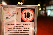 Sign: "18  For Adults Only. Rolling Joint Outside Is Forbiden." A Sign At The Entrance To A Coffee Shop Where The Use Of Marijuana Is Legalized In Amsterdam, Netherlands. Cannabis In Holland.Weed Shop