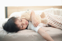 Child Little Girl Sleeps In The Bed With A Toy Teddy Bear