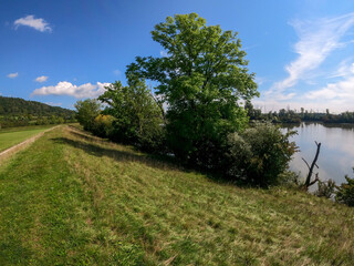 Sticker - Natural view of a greenfield near a lake under a clear blue sky