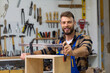 © DusanJelicic - A young carpenter makes a wooden box and looks at the camera with a smile