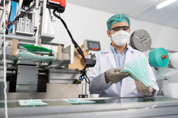 Wall Mural - male factory worker are producing medical face masks, counting and checking of quality from machine