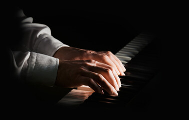 Musician plays on piano with two hands. Isolated focus and light. Male bright hands