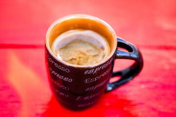 Poster - Top view of a cup of freshly made coffee on a red wooden surface