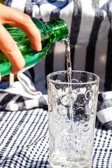 Poster - Man pouring water from a green bottle into a glass