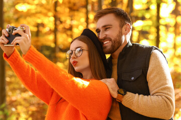 Wall Mural - Young loving couple taking selfie in autumn park