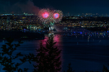 Canvas Print - Beautiful shot of bright colorful exploding fireworks in a city over water