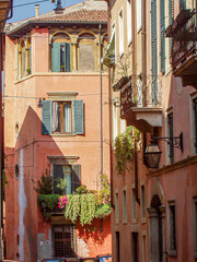 Sticker - Beautiful shot of a pink building with flowers on a balcony on a sunny d