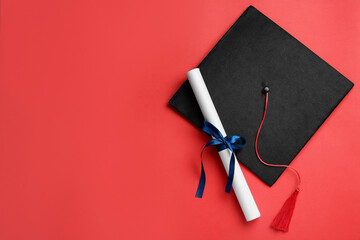 Wall Mural - Graduation hat and diploma on red background, flat lay. Space for text