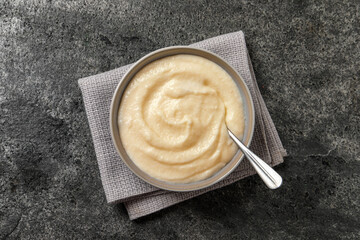 Bowl with delicious semolina pudding on grey table, top view