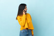 © luismolinero - Caucasian girl isolated on blue background keeping a conversation with the mobile phone with someone