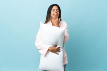 Young Woman In Pajamas Over Isolated Background In Pajamas And Holding A Pillow And Yawning