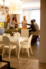 Wall Mural - Group of young people preparing meal, drinking white wine and having a good time