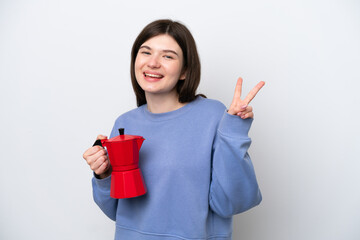 Wall Mural - Young Russian woman holding coffee pot isolated on white background smiling and showing victory sign