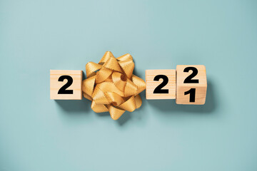 Wall Mural - Flipping wooden cube block for change 2021 to 2022 with golden ribbon bow for preparation merry Christmas and happy new year concept.