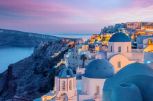 Colorful And Dramatic Sunset With Night Lights In Mediterranean Town Of Oia, Santorini, Greece, Europe