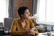 © fizkes - Thoughtful young African American businesswoman in glasses looking in distance, holding cellphone in hands, feeling confused getting message or email with unpleasant news, considering problem solution