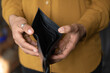 © fizkes - Close up young African American unemployed woman holding opened empty black leather wallet. feeling stressed without cash, having financial problems, suffering from lack of money, bankruptcy concept.