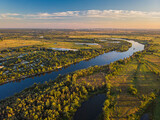 Fototapeta Miasto - Aerial drone view. The bend of a wide river among green meadows.