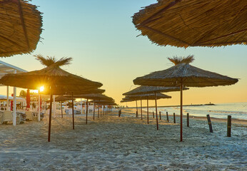 Seashore, sand beach with umbrellas and sunbeds on background of the sea and sky