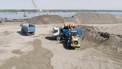 Poster - The excavator loads the dump truck with sand and soil. Scene. Aerial view of the equipment prepares the construction site for the construction of an apartment building.