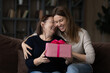 © fizkes - Happy birthday mommy. Affectionate young woman adult daughter sit on sofa embrace excited older mum greet aged parent with Christmas. Caring female grown child give senior mom present box on March 8