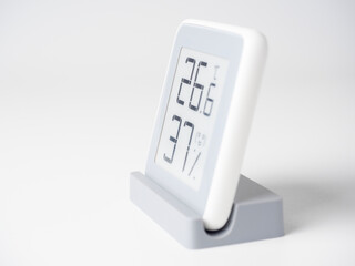 Wall Mural - A home weather station standing on a white background is a modern device with a screen showing the temperature and humidity in the room. Side view