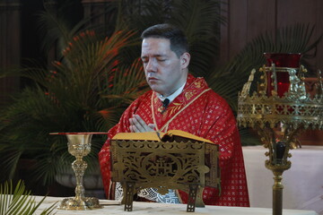 Wall Mural - A priest celebrates a catholic mass dressed in a red chasuble 