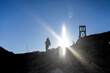 © ecummings00 - Man climbs a mountaintop wards an old head frame carrying gear on shoulders. Highly sunflared