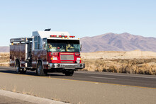 Red And White Fire Truck Driving Down A Road In The Desert Responding To An Emergency Call
