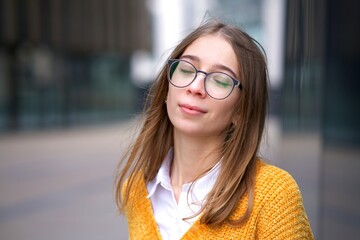 Portrait of joyful beautiful relaxed girl, young pretty woman in glasses enjoying good summer day, breathing deeply, breath deep fresh air with her eyes closed. Enjoyment, happiness, freedom concept.