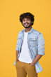 © insta_photos - Smiling young curly indian cool positive guy standing isolated on yellow background. Happy ethnic stylish millennial man wearing blue casual t-shirt looking at camera posing for portrait. Vertical