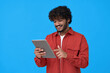 © insta_photos - Happy indian young man using digital tablet isolated on blue background. Smiling ethnic student guy holding pad remote learning in app, studying or communicating, surfing online, reading e book.