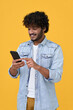 Leinwandbild Motiv Happy indian young man using cell phone isolated on yellow background. Smiling ethnic hipster guy holding smartphone playing game in app, dating buying online in ecommerce store on cellphone. Vertical