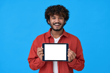 Happy young indian man showing tablet computer big mockup white blank empty template screen isolated on blue background presenting holding pad website offer or application ads concept.