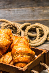 Poster - Vertical shot of croissants in a wooden crate